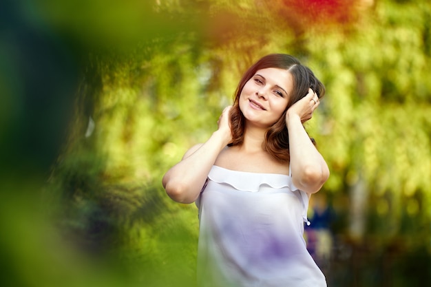 Joven hermosa mujer feliz al aire libre en el jardín de la ciudad