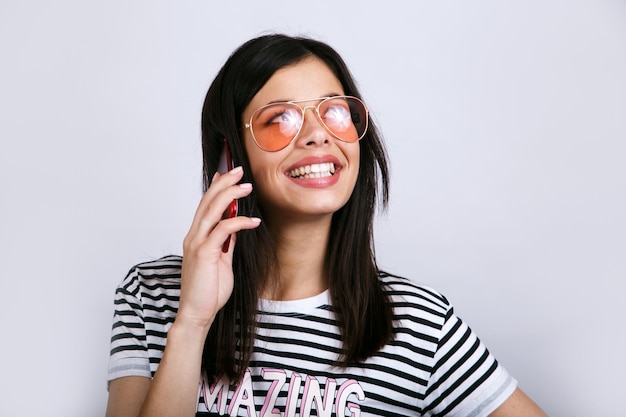 Joven hermosa mujer feliz con gafas de sol usando un teléfono inteligente