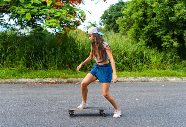 Joven y hermosa mujer con una gorra montando en una patineta y riendo