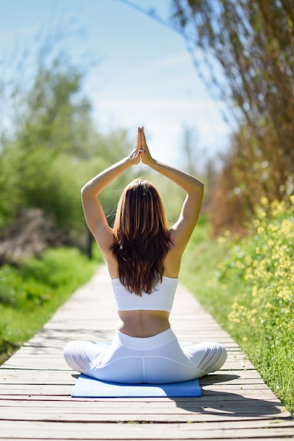 Joven hermosa mujer haciendo yoga en la naturaleza