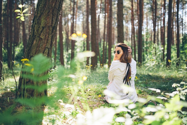 Joven hermosa mujer hippie camina en el bosque de verano se ríe baila y disfruta de la vida y la naturaleza