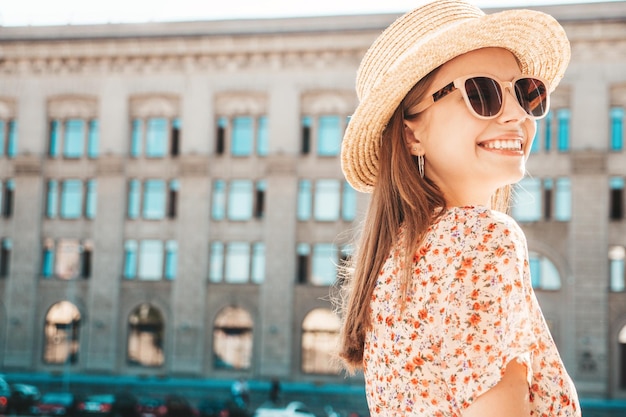 Joven hermosa mujer hipster sonriente en ropa de verano de moda Mujer sexy despreocupada posando en el fondo de la calle al atardecer Modelo positivo al aire libre Alegre y feliz con gafas de sol y sombrero