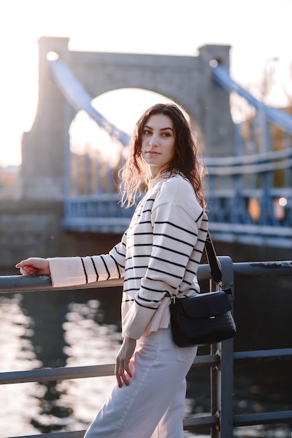 Joven hermosa mujer hipster sonriente en ropa de verano de moda Sexy modelo despreocupada posando en el fondo de la calle Europa al atardecer Mujer morena positiva Alegre y feliz