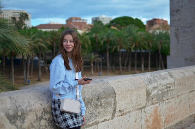 Foto joven y hermosa mujer hipster usando el teléfono móvil en la ciudad al atardecer