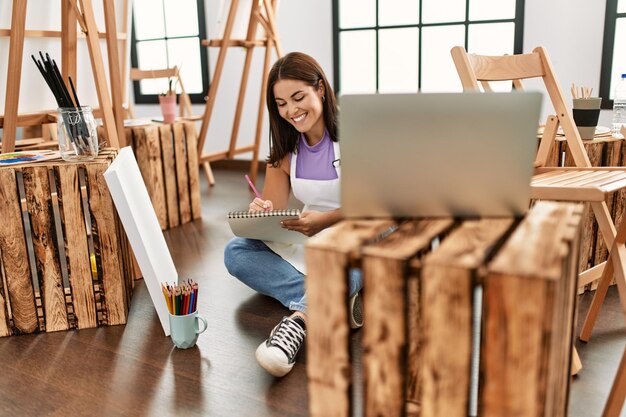 Joven hermosa mujer hispana artista mirando dibujo portátil en el estudio de arte