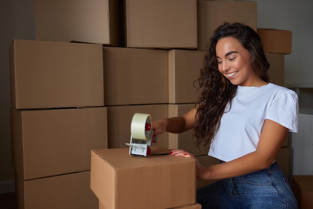 Joven hermosa mujer hispana sonriendo confiada caja de cartón de embalaje en el nuevo hogar