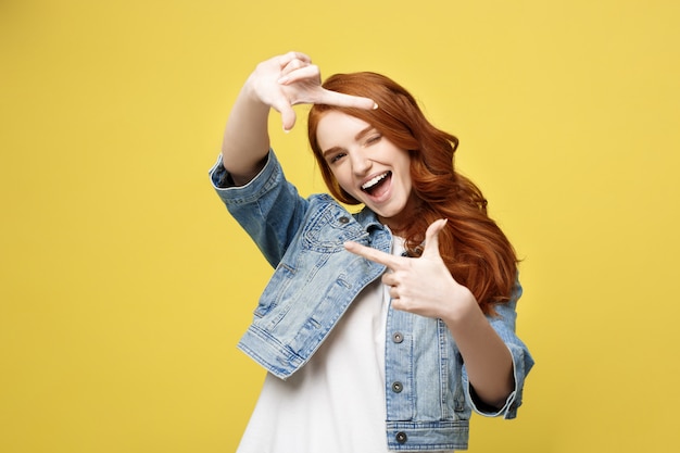 Joven hermosa mujer de jengibre con pecas sonriendo haciendo un marco de cámara