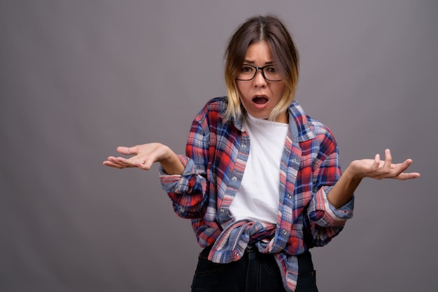 Joven hermosa mujer kazaja contra la pared gris