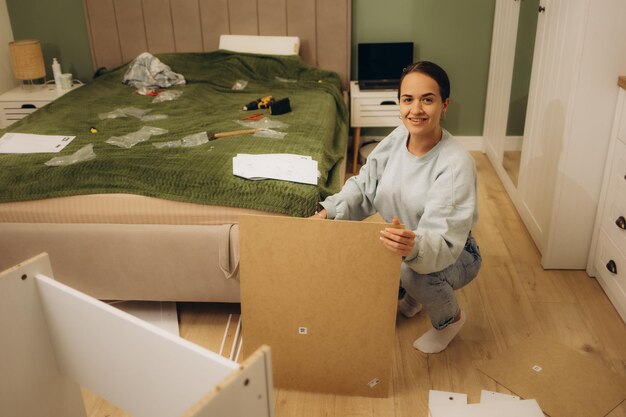 Foto joven y hermosa mujer montando muebles en casa.