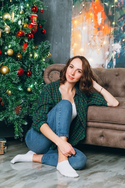 Joven hermosa mujer morena en el árbol de Navidad