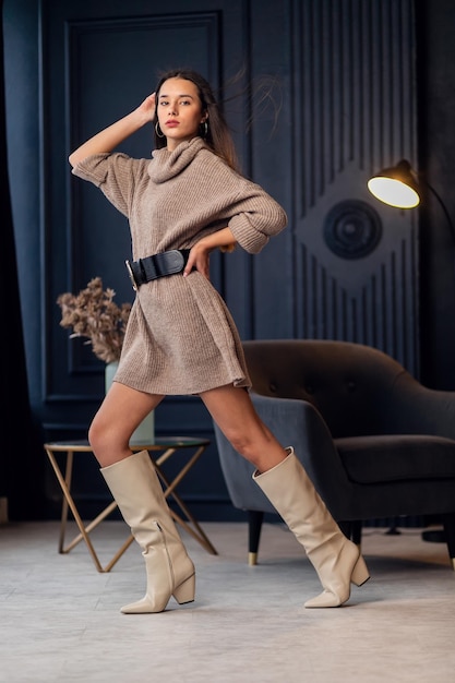 Joven hermosa mujer morena con botas beige en un hermoso interior Retrato de cuerpo entero Joven mujer elegante con aspecto elegante beige Chica bonita con cabello largo y ondulado Morena Dama de moda