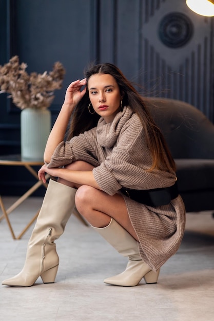 Joven hermosa mujer morena con botas beige en un hermoso interior Retrato de cuerpo entero Joven mujer elegante con aspecto elegante beige Chica bonita con cabello largo y ondulado Morena Dama de moda