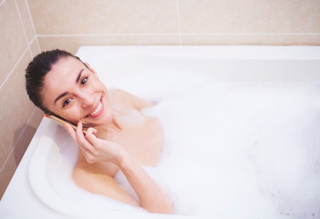 Joven hermosa mujer morena está tomando el procedimiento de baño en casa