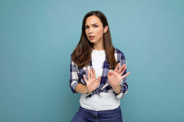 Joven hermosa mujer morena insatisfecha seria con emociones sinceras con camisa a cuadros de moda