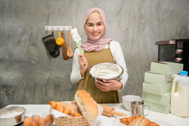 Joven hermosa mujer musulmana está horneando en su negocio de panadería y cafetería de cocina