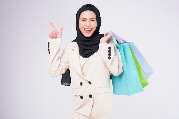 Joven hermosa mujer musulmana en traje sosteniendo coloridas bolsas de compras sobre estudio de fondo blanco