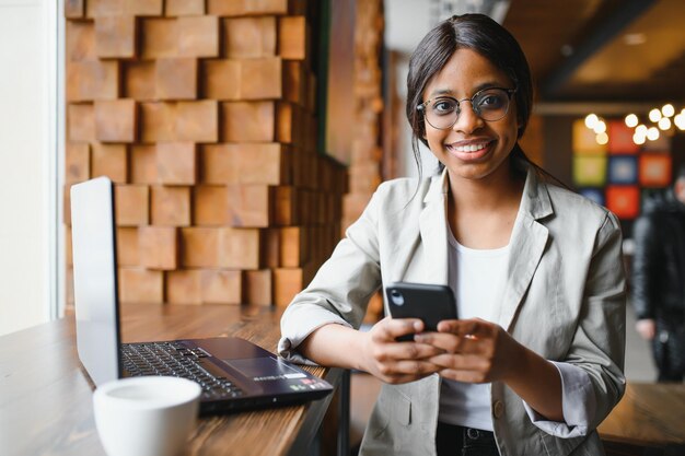 Joven y hermosa mujer de negocios afroamericana que usa una laptop mientras trabaja en un café