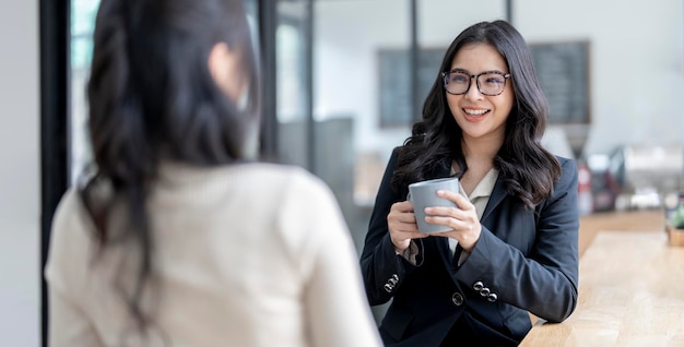 Joven y hermosa mujer de negocios asiática divirtiéndose hablando con sus colegas durante un descanso del trabajo