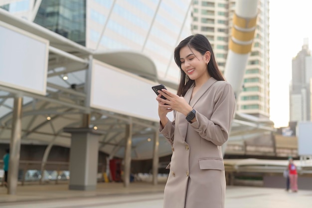 Una joven y hermosa mujer de negocios está usando un teléfono inteligente en el concepto de estilo de vida de la ciudad de la tecnología de negocios de la ciudad moderna