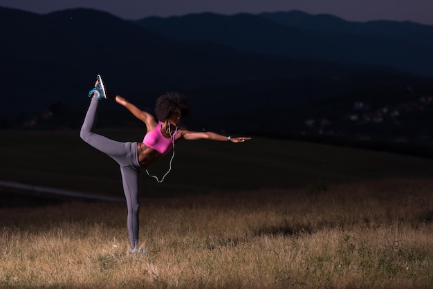 joven hermosa mujer negra haciendo ejercicios de yoga en la naturaleza de una hermosa noche de verano
