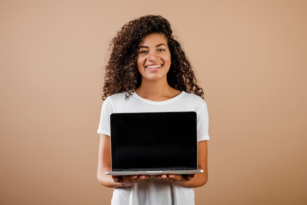 Joven hermosa mujer negra con laptop en manos aisladas sobre marrón