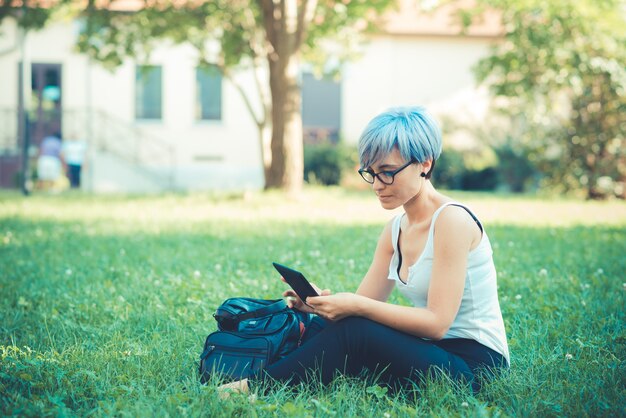 joven hermosa mujer de pelo corto azul hipster usando tableta