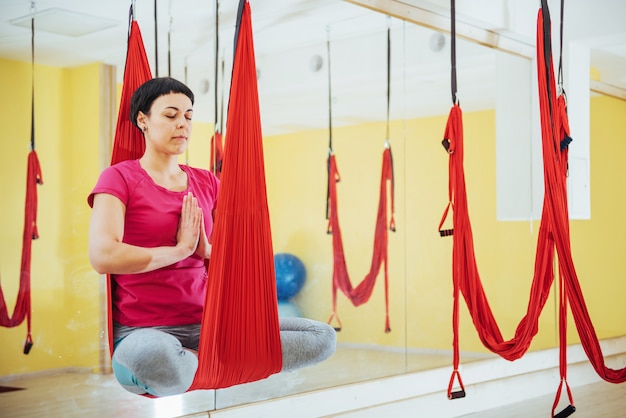 Joven hermosa mujer practicando yoga Volar con una hamaca en estudio.