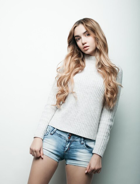 Joven hermosa mujer rizada posando con camisetas blancas sobre fondo blanco.