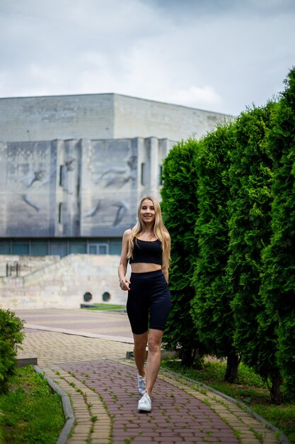 Joven hermosa mujer rubia deportiva con una camiseta negra y pantalones cortos deportivos ajustados negros