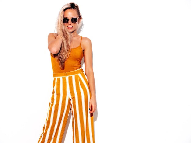 Foto joven hermosa mujer rubia sonriente en ropa amarilla de moda de verano mujer despreocupada aislada en blanco en el estudio modelo positivo divirtiéndose en el interior alegre y feliz en gafas de sol