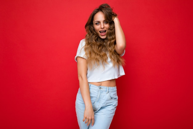 Joven hermosa mujer rubia vestida con camiseta blanca mujer positiva muestra facial