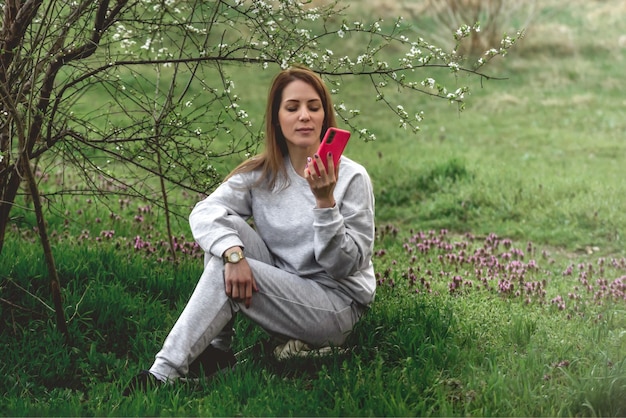 joven hermosa mujer sentada en el suelo en un parque de primavera