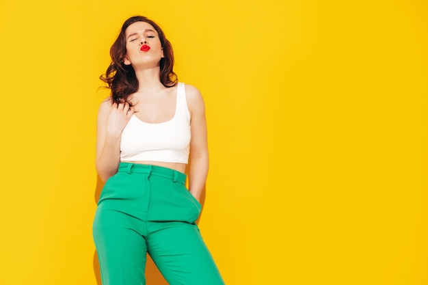 Joven hermosa mujer sonriente en ropa de verano de moda Mujer sexy despreocupada posando junto a la pared amarilla en el estudio Modelo positivo divirtiéndose y volviéndose loco Alegre y feliz En gafas de sol