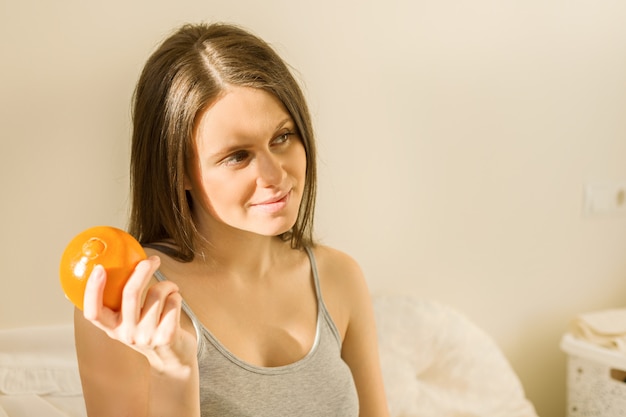 Joven hermosa mujer sonriente sosteniendo una naranja