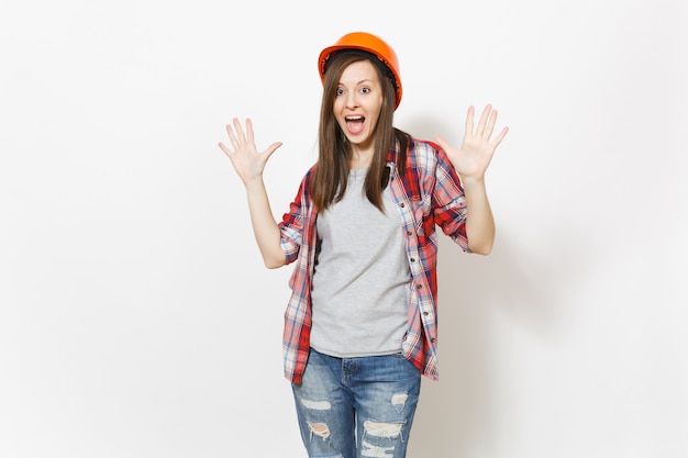 Joven hermosa mujer sorprendida en casco naranja de construcción protectora extendiendo las manos con espacio de copia aislado sobre fondo blanco. Instrumentos para la renovación de la habitación del apartamento. Reparar el concepto de hogar.