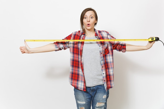 Foto joven hermosa mujer sorprendida en ropa casual con cinta métrica aislada sobre fondo blanco. instrumentos, accesorios, herramientas para la renovación de la habitación del apartamento. reparar el concepto de hogar. área de publicidad.