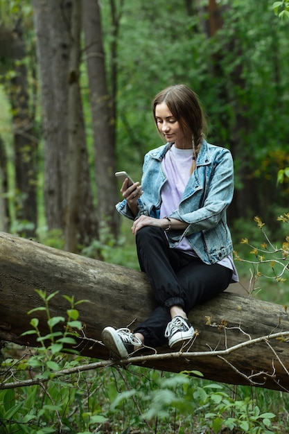 joven hermosa mujer turista en el bosque en un paseo mirando a través de su teléfono