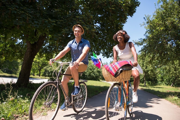 un joven y una hermosa niña afroamericana disfrutando de un paseo en bicicleta en la naturaleza en un día soleado de verano