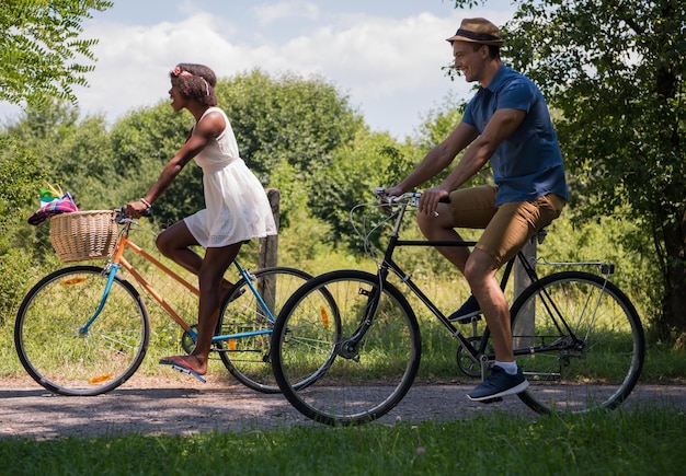 un joven y una hermosa niña afroamericana disfrutando de un paseo en bicicleta en la naturaleza en un día soleado de verano