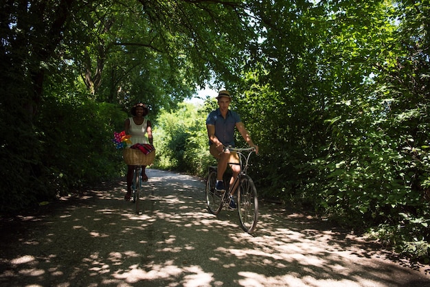 un joven y una hermosa niña afroamericana disfrutando de un paseo en bicicleta en la naturaleza en un día soleado de verano