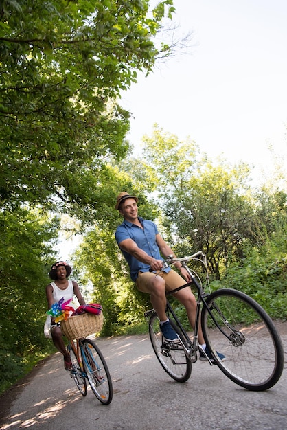 un joven y una hermosa niña afroamericana disfrutando de un paseo en bicicleta en la naturaleza en un día soleado de verano