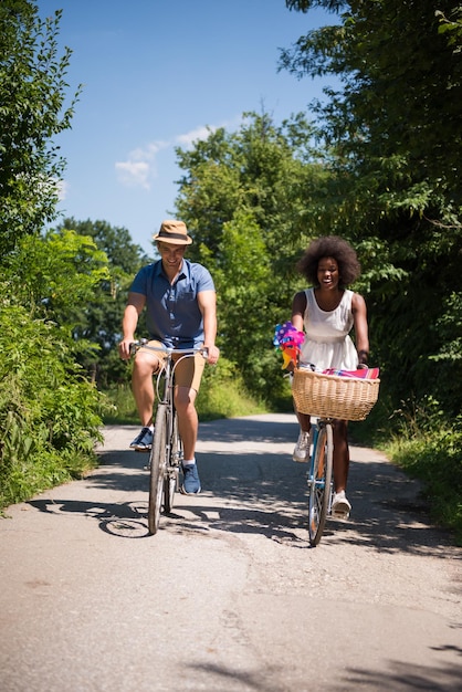 un joven y una hermosa niña afroamericana disfrutando de un paseo en bicicleta en la naturaleza en un día soleado de verano