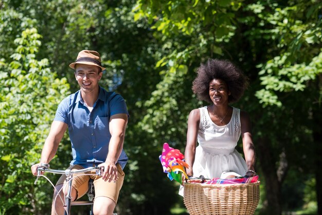 un joven y una hermosa niña afroamericana disfrutando de un paseo en bicicleta en la naturaleza en un día soleado de verano