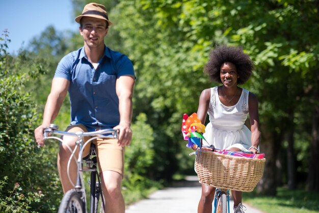 un joven y una hermosa niña afroamericana disfrutando de un paseo en bicicleta en la naturaleza en un día soleado de verano