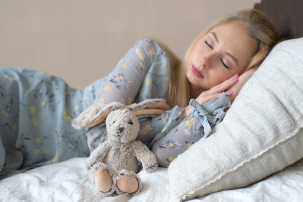 Joven hermosa niña durmiendo en la cama con juguete para niños como niño