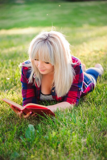 Joven hermosa niña leyendo un libro al aire libre