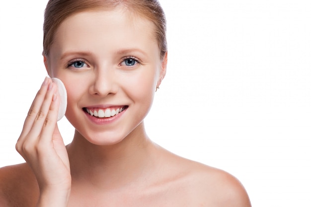 Joven hermosa niña limpia el maquillaje de ojos