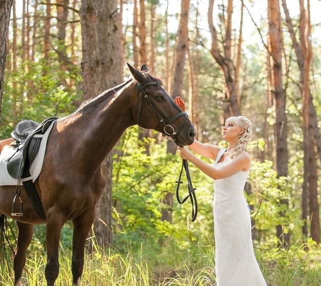 Joven hermosa novia y caballo en la naturaleza