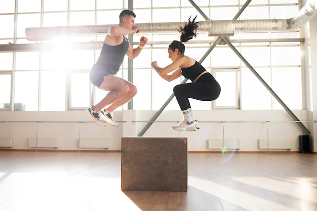 Foto joven y hermosa pareja atlética en ropa deportiva en el entrenamiento de crossfit en la sala de fitness