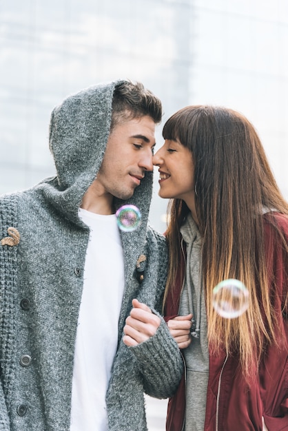 Joven hermosa pareja enamorada abrazándose en medio de la calle de una manera romántica con pompas de jabón